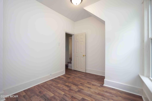 spare room featuring baseboards and dark wood-style flooring