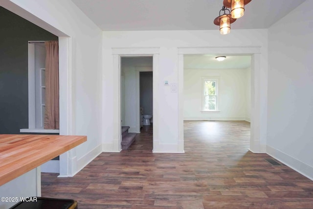unfurnished dining area featuring dark wood finished floors and baseboards