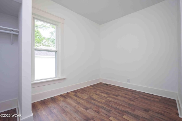 spare room with baseboards and dark wood-style flooring