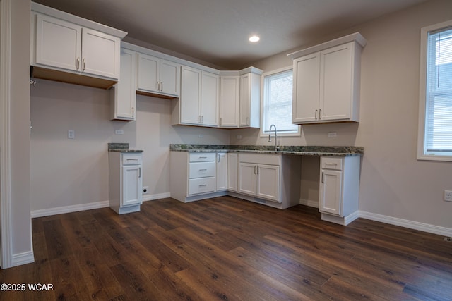 kitchen featuring a wealth of natural light, dark hardwood / wood-style floors, dark stone countertops, and white cabinets