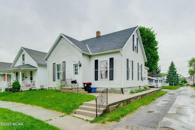 608 W Pearl St, Wapakoneta, OH 45895 - view of front of home with covered porch, roof with shingles, a chimney, and a front yard