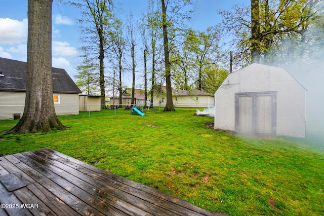 view of yard featuring a storage shed, a playground, a deck, an outdoor structure, and a fenced backyard