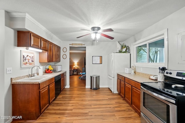 kitchen with light wood-style flooring, white appliances, ceiling fan, a sink, and light countertops