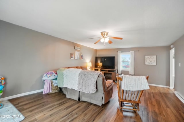 living room featuring baseboards, a ceiling fan, and wood finished floors