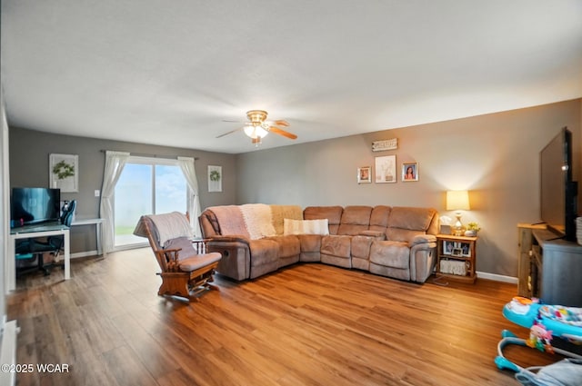 living room with light wood finished floors, baseboards, and a ceiling fan