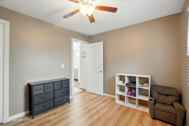 sitting room with a ceiling fan, baseboards, and light wood-type flooring