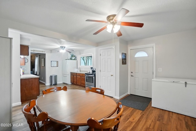 dining room featuring light wood finished floors, baseboards, and a ceiling fan