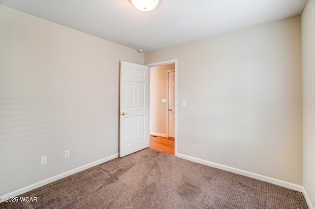 unfurnished room with carpet and baseboards