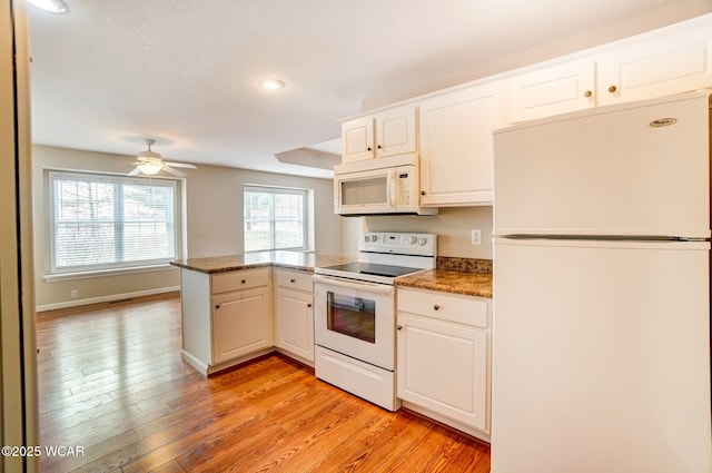 kitchen featuring light wood-style flooring, white appliances, white cabinets, and a peninsula