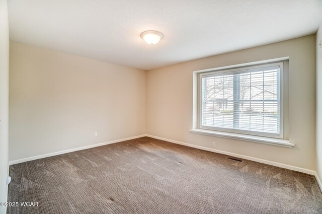 carpeted empty room featuring visible vents and baseboards