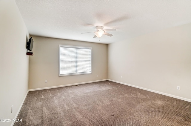 carpeted spare room with ceiling fan, a textured ceiling, and baseboards