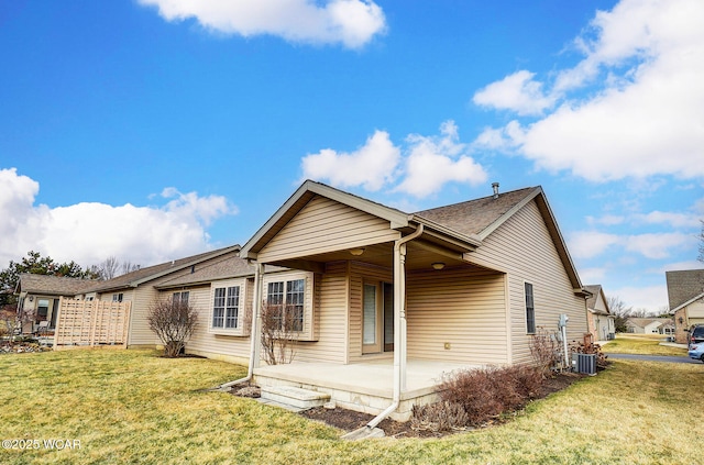 back of property with a shingled roof, central AC, a lawn, and a patio