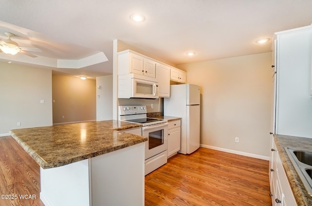 kitchen featuring light wood finished floors, recessed lighting, white cabinetry, white appliances, and a peninsula