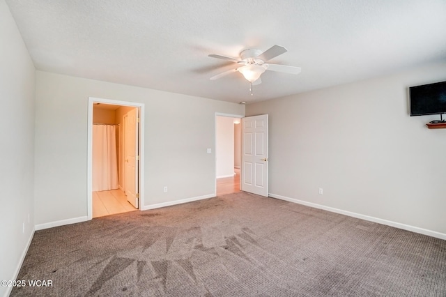 unfurnished bedroom with ensuite bathroom, carpet flooring, a ceiling fan, and baseboards