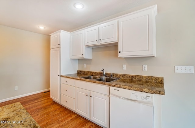 kitchen featuring white dishwasher, a sink, white cabinetry, light wood-type flooring, and dark countertops