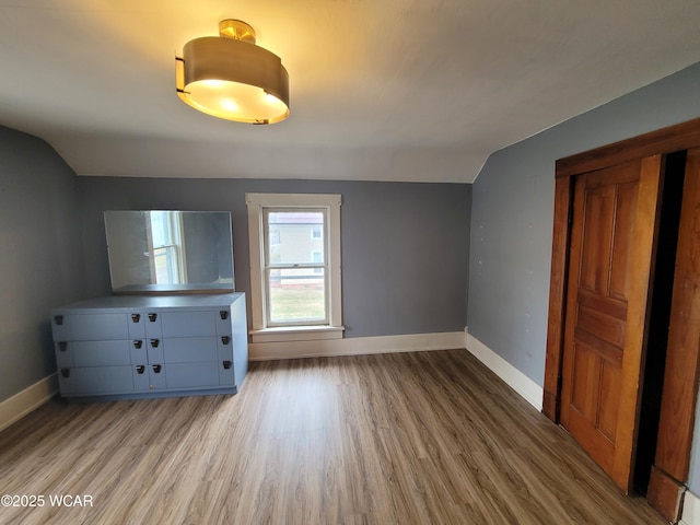 unfurnished bedroom with lofted ceiling and light wood-type flooring