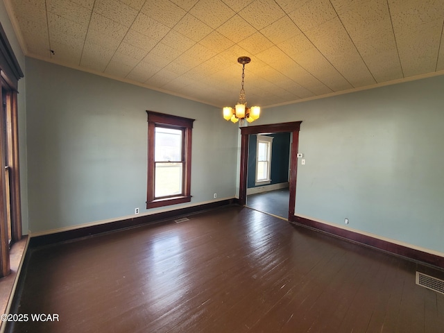 spare room with a notable chandelier, crown molding, and dark wood-type flooring