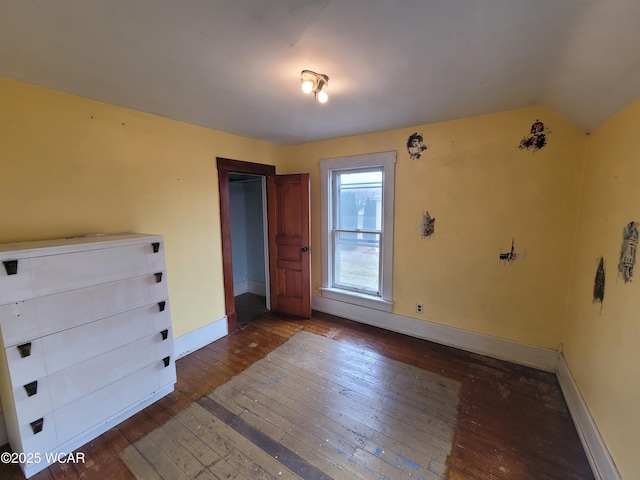 unfurnished bedroom with vaulted ceiling and dark hardwood / wood-style floors