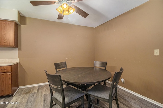 dining space with light wood-style floors, baseboards, and a ceiling fan