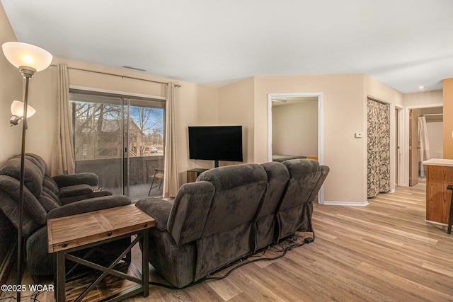 living room featuring light wood-type flooring, baseboards, and visible vents