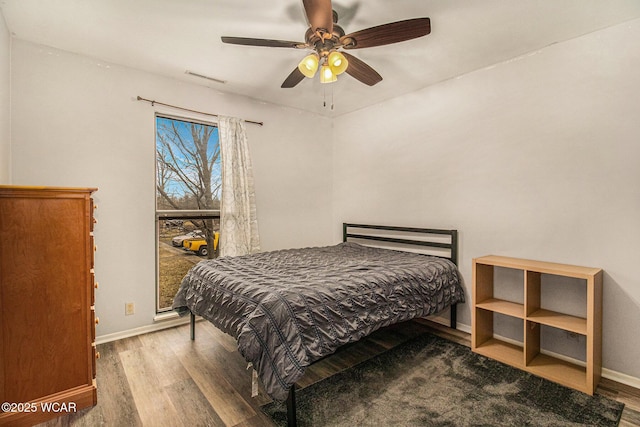 bedroom with ceiling fan, wood finished floors, visible vents, and baseboards