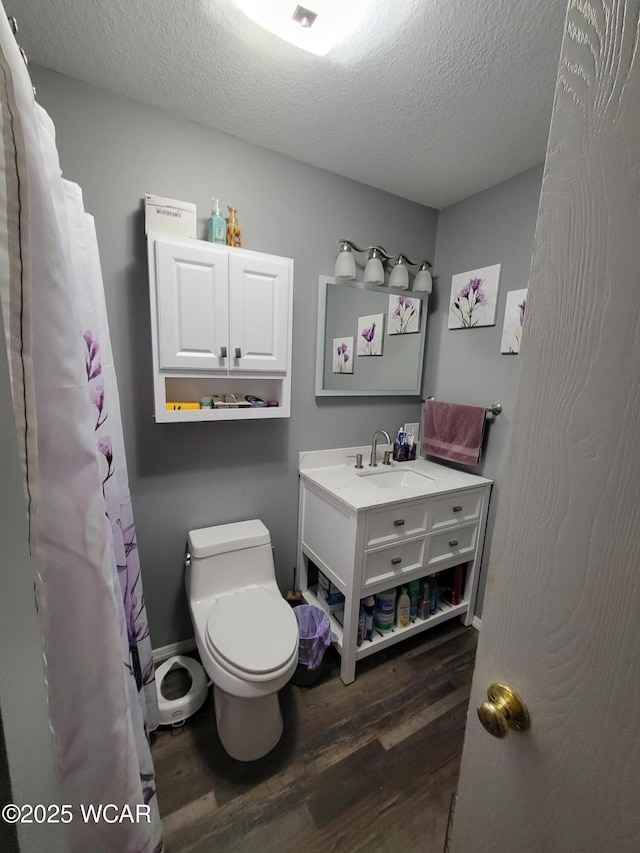 bathroom with vanity, a textured ceiling, toilet, and wood finished floors