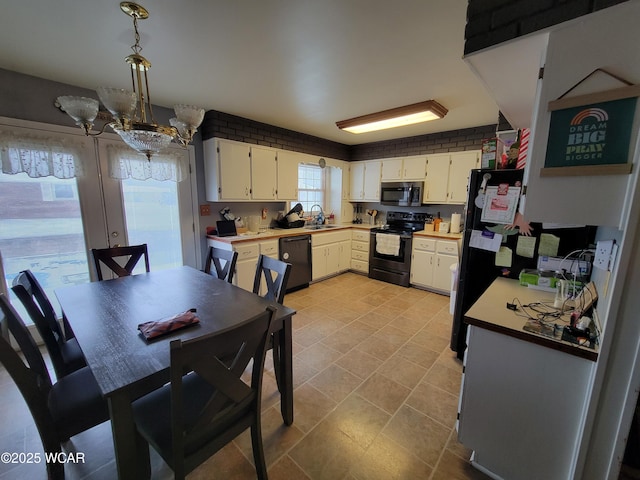 kitchen with decorative light fixtures, a sink, light countertops, black appliances, and a notable chandelier