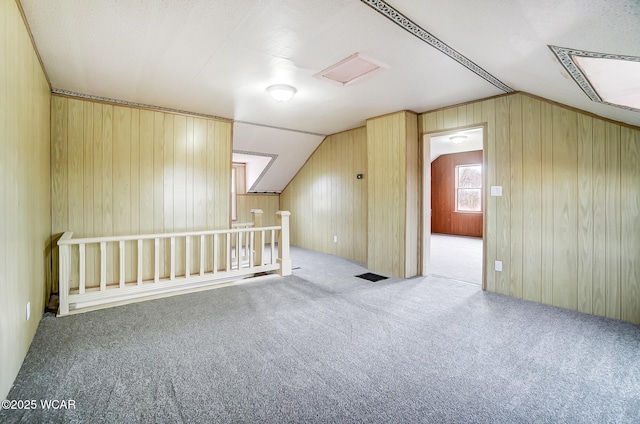 bonus room featuring light colored carpet, lofted ceiling, and wooden walls