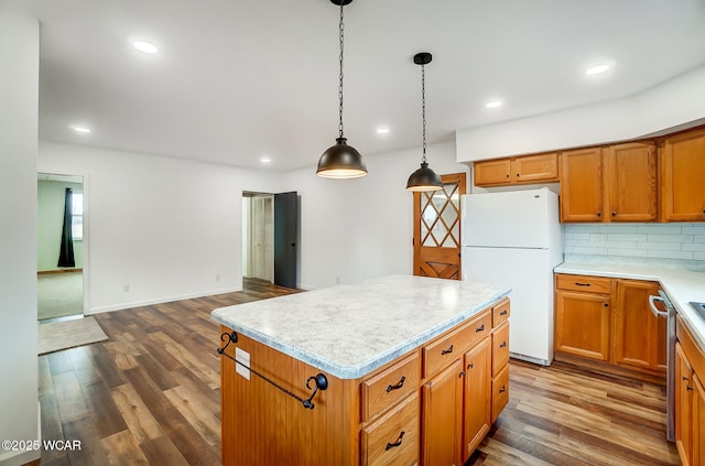 kitchen with a center island, hanging light fixtures, dark hardwood / wood-style flooring, white fridge, and backsplash