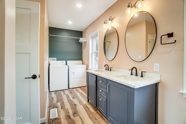 bathroom with hardwood / wood-style flooring, washing machine and dryer, and vanity