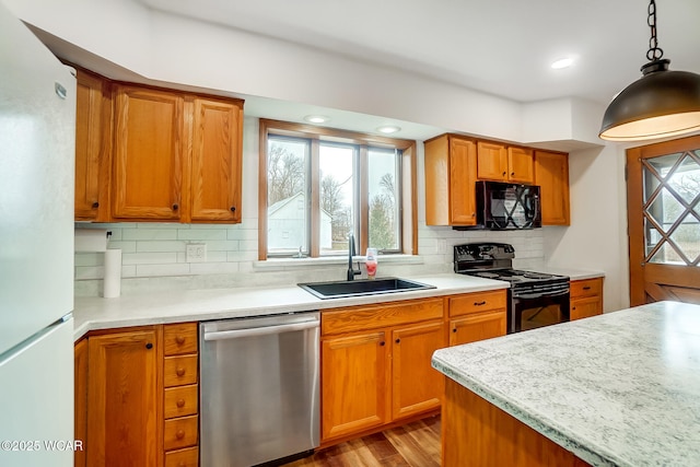 kitchen featuring sink, tasteful backsplash, pendant lighting, light hardwood / wood-style floors, and black appliances