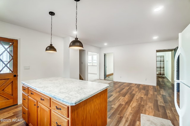 kitchen with dark wood-type flooring, white fridge, a center island, and hanging light fixtures