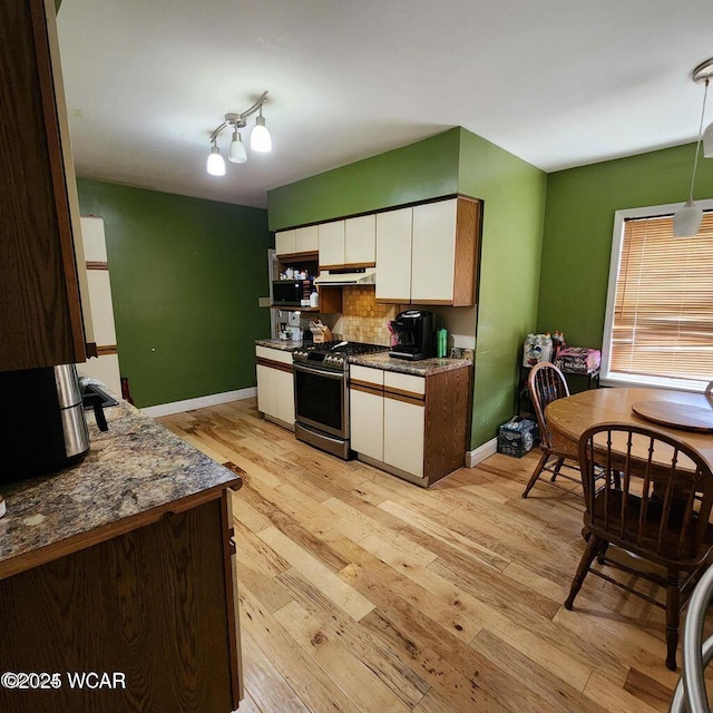 kitchen featuring tasteful backsplash, white cabinets, light stone counters, gas stove, and light hardwood / wood-style flooring