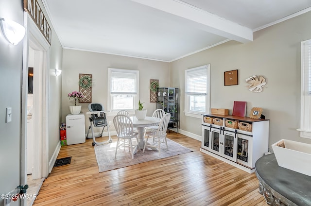 dining space with light wood-style flooring, visible vents, baseboards, and ornamental molding