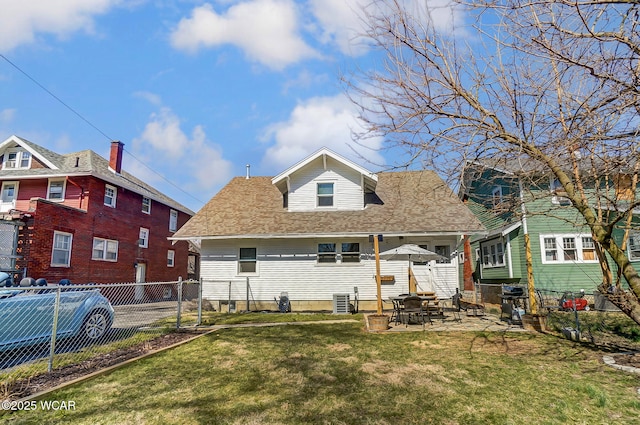 view of front of home with a patio, fence, a front yard, and a shingled roof