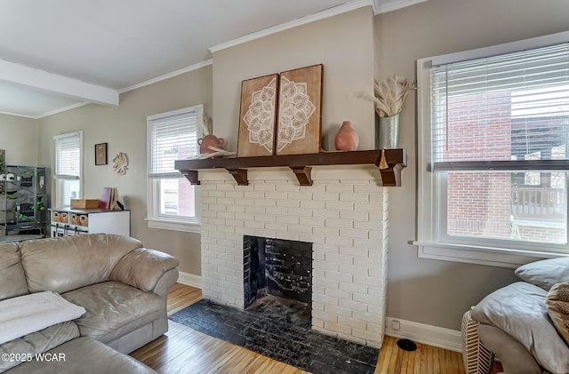 living area with ornamental molding, a fireplace, baseboards, and wood finished floors