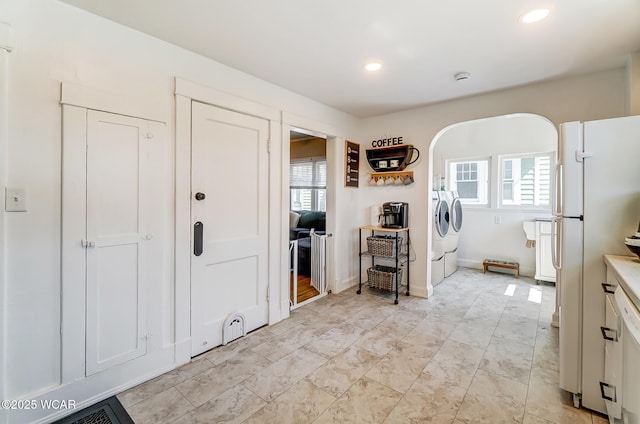 kitchen featuring a wealth of natural light, recessed lighting, freestanding refrigerator, and washing machine and clothes dryer