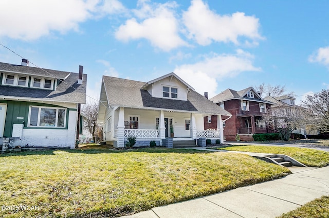 bungalow-style home with a front yard, brick siding, covered porch, and roof with shingles