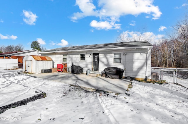 snow covered rear of property featuring a storage unit