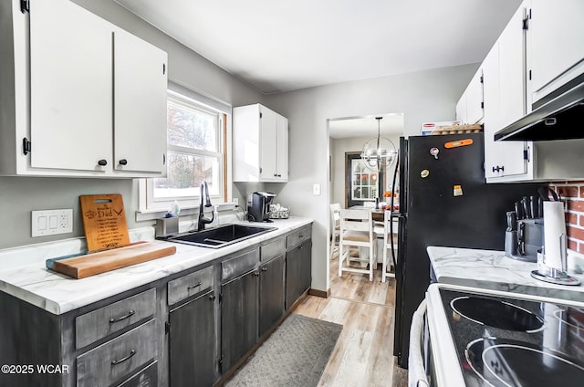 kitchen featuring sink, light hardwood / wood-style flooring, a chandelier, and white cabinets