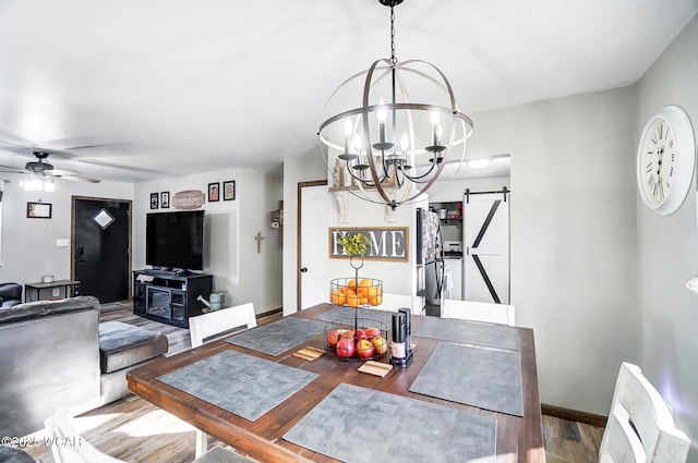 dining space featuring hardwood / wood-style floors, ceiling fan with notable chandelier, and a barn door