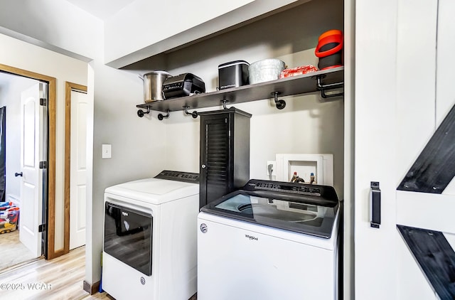 clothes washing area featuring separate washer and dryer and light hardwood / wood-style flooring