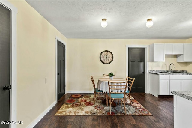 dining room with sink, dark wood-type flooring, and a textured ceiling