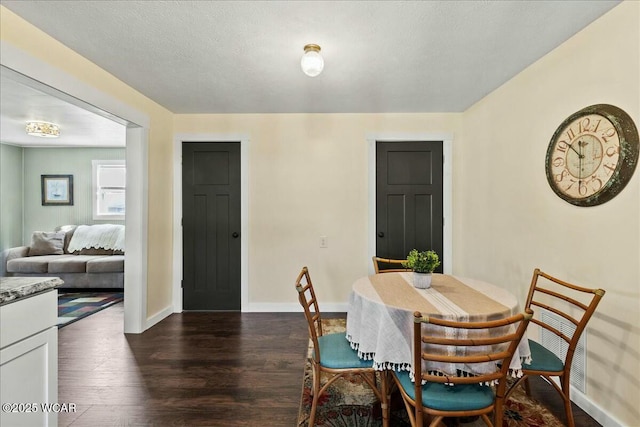 dining room featuring dark wood-type flooring and a textured ceiling