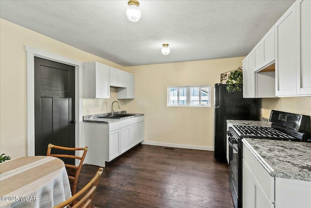 kitchen featuring dark wood-type flooring, sink, black gas range oven, light stone countertops, and white cabinets