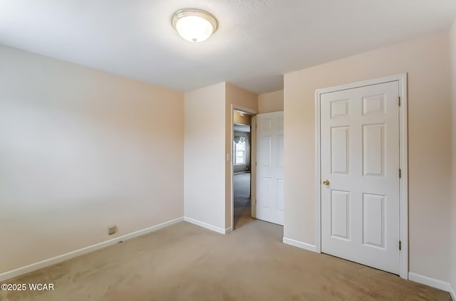 unfurnished bedroom with light colored carpet and baseboards