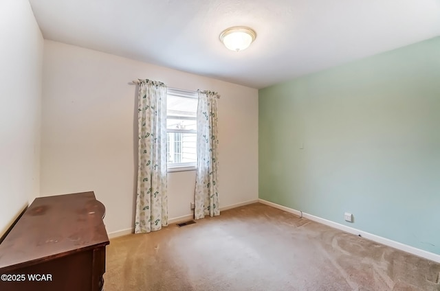 carpeted empty room featuring baseboards and visible vents