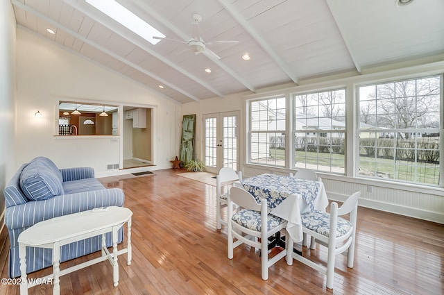 interior space with light wood finished floors, visible vents, lofted ceiling with skylight, ceiling fan, and french doors