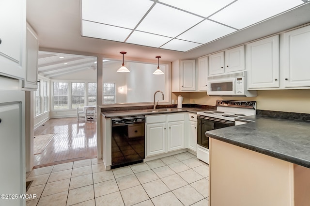 kitchen with dark countertops, white appliances, a sink, and a peninsula