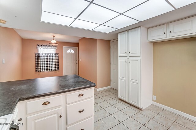 kitchen featuring decorative light fixtures, dark countertops, light tile patterned flooring, white cabinetry, and baseboards